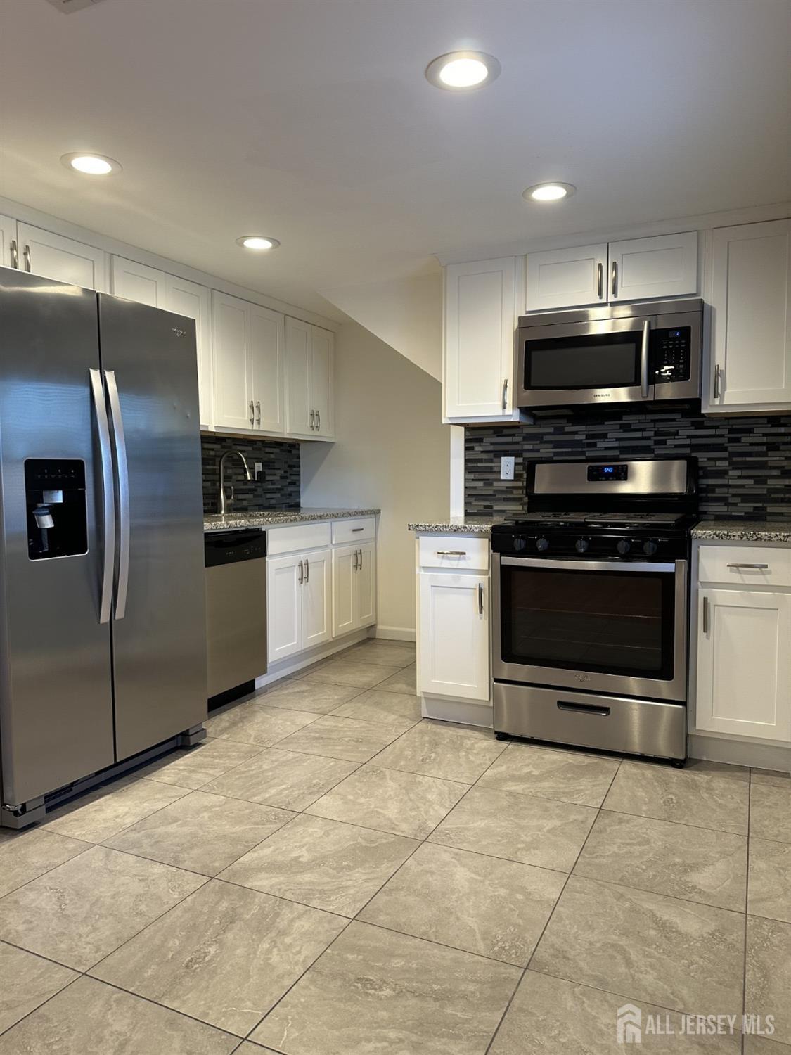 a kitchen with stainless steel appliances granite countertop a stove a refrigerator and a microwave