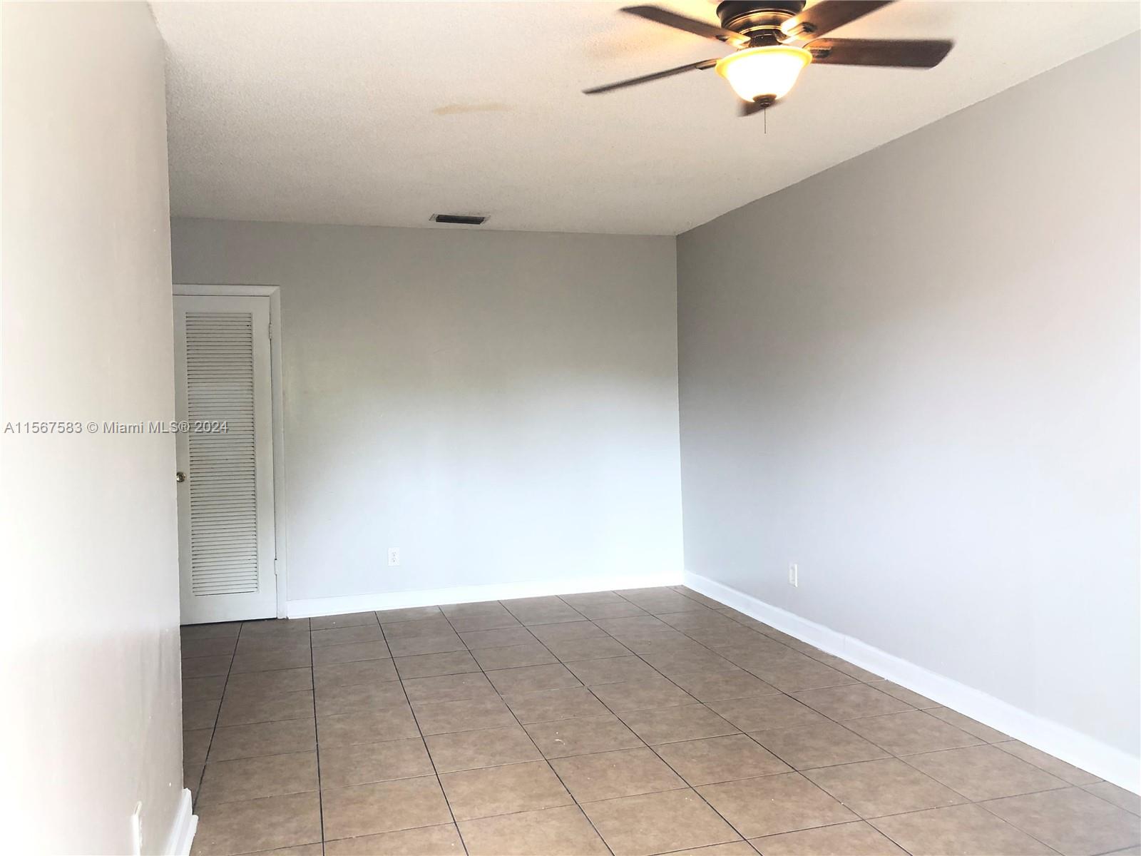 an empty room with a ceiling fan and carpet