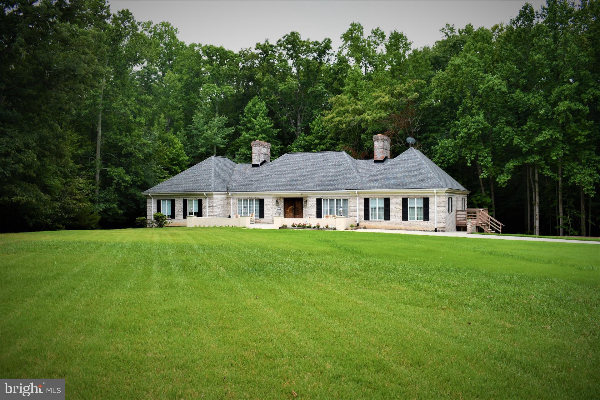 a view of a big house with a big yard and large trees