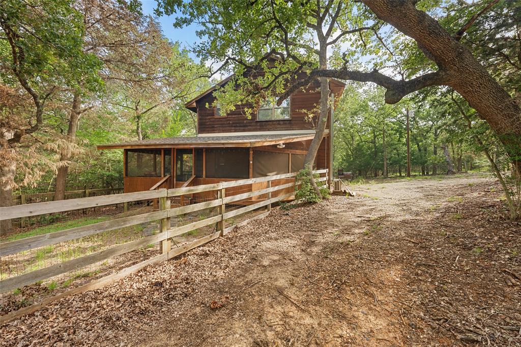 a view of house with large trees and wooden fence