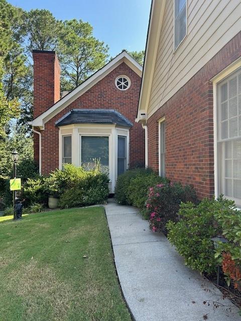 a view of a house with a small yard plants and a large tree