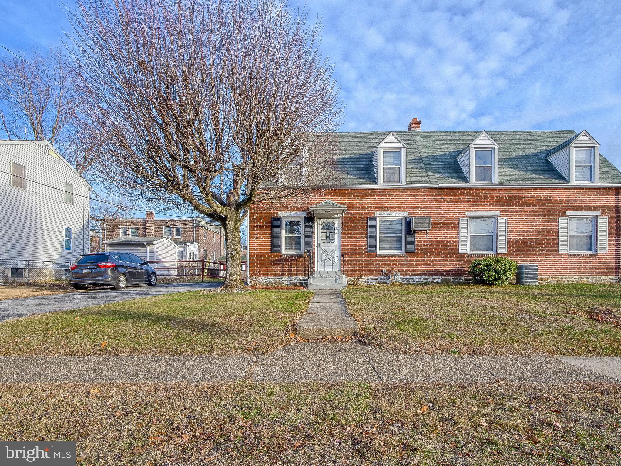 a view of a big yard in front of a brick house with a large tree