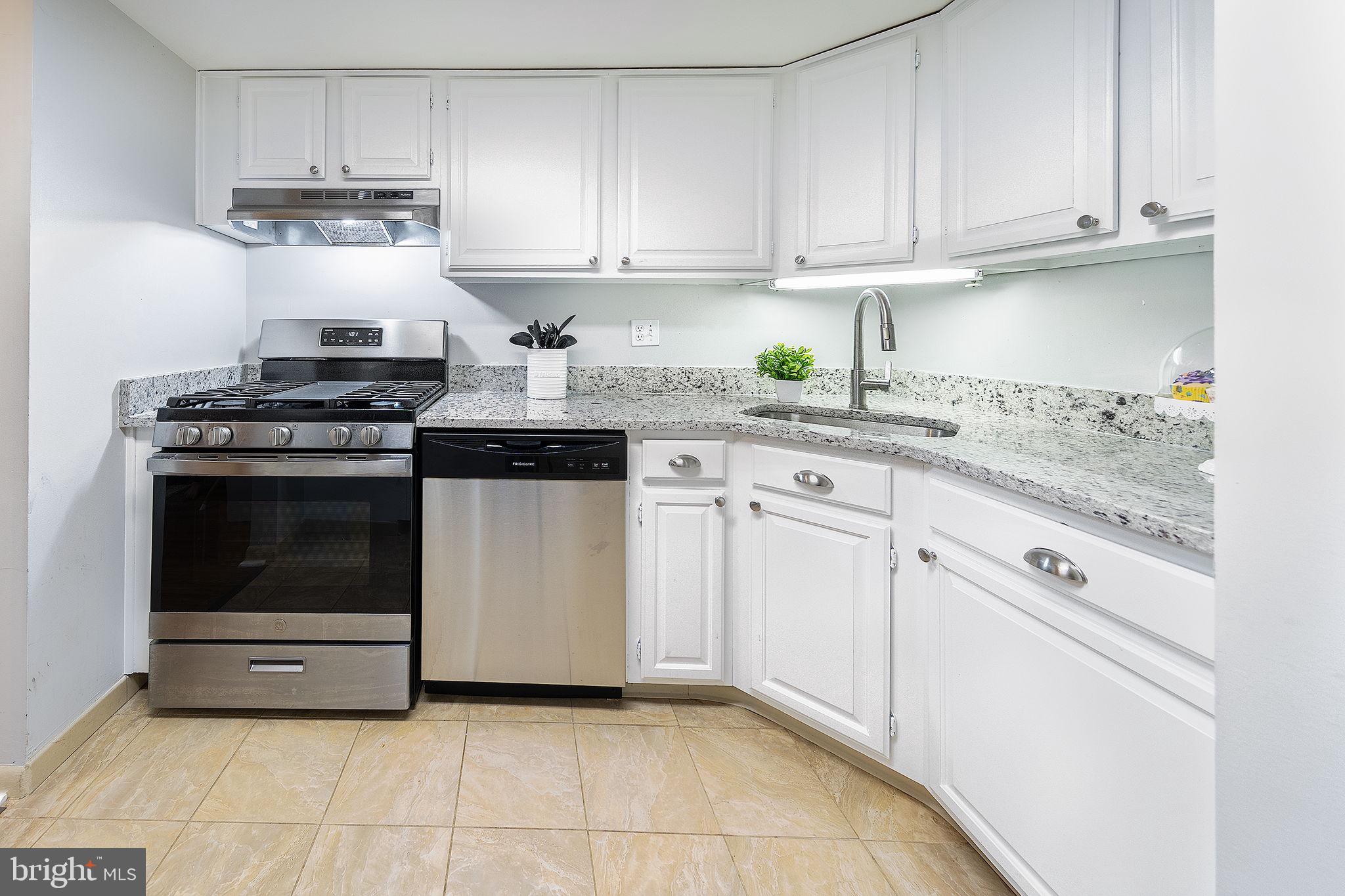 a kitchen with granite countertop white cabinets and appliances