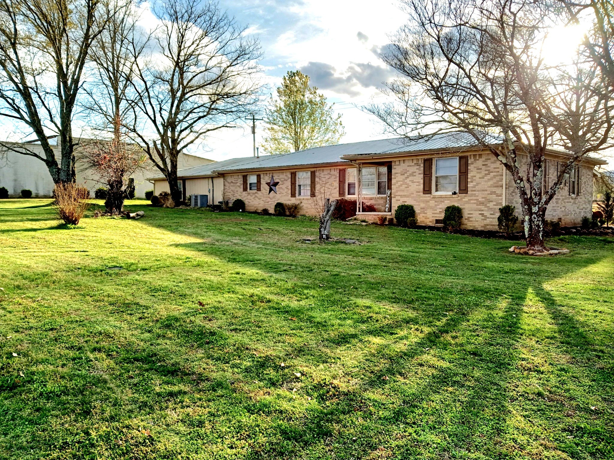 a view of a house with a big yard and large trees