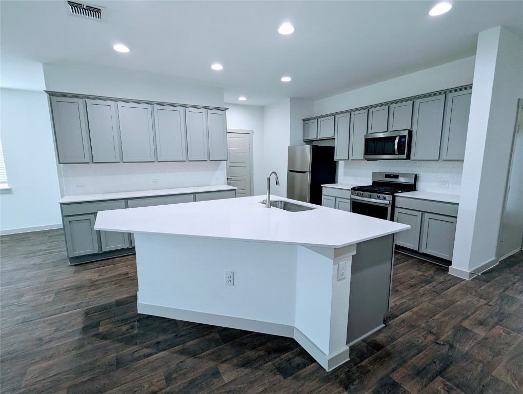 a kitchen with kitchen island a sink stainless steel appliances and cabinets