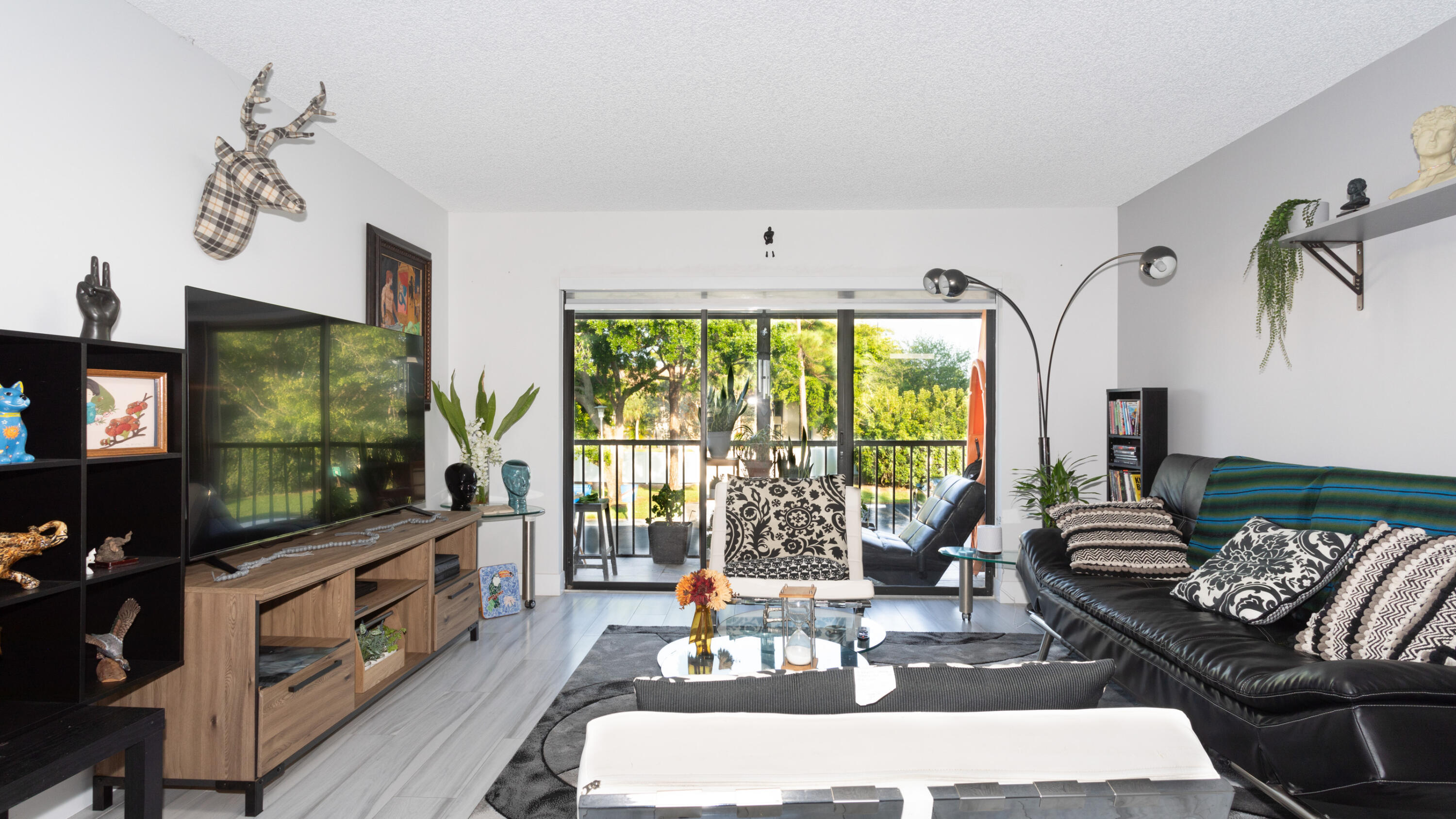 a living room with furniture a flat screen tv and a floor to ceiling window