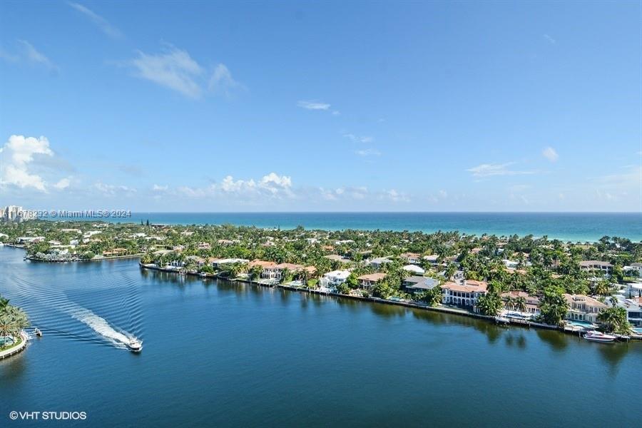 an aerial view of ocean and residential houses with outdoor space