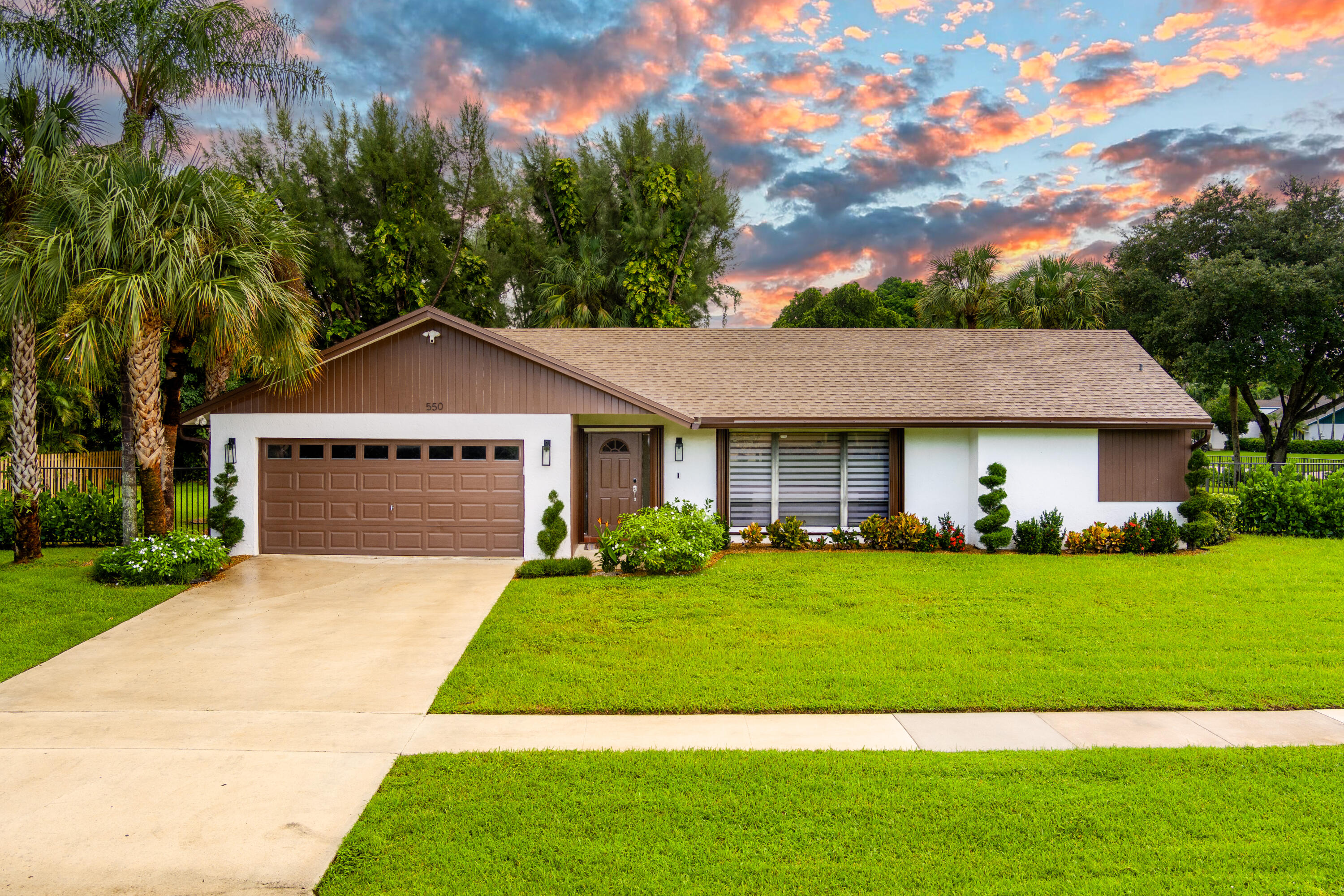 a front view of a house with a garden and trees