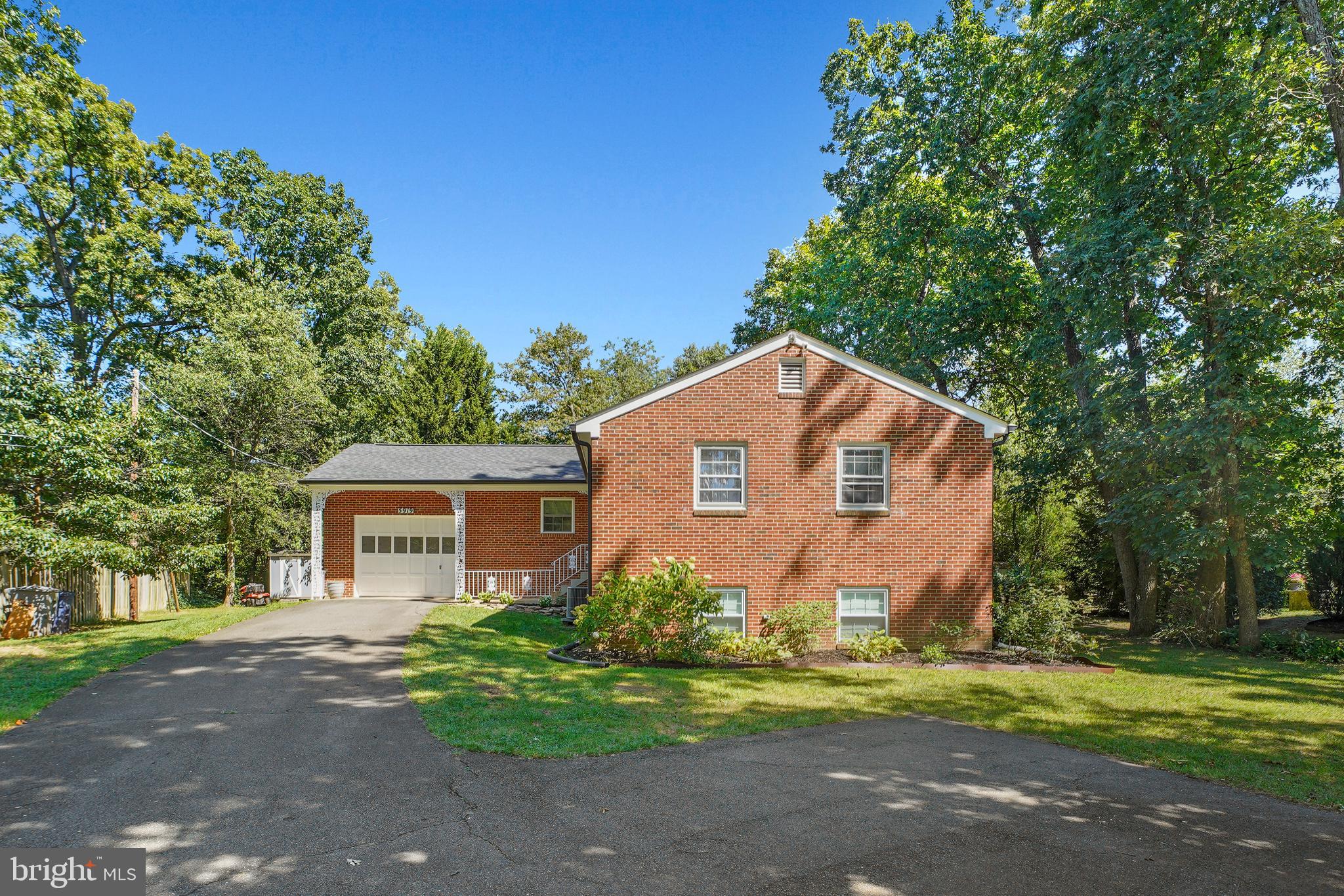 a view of a house with a yard and large trees