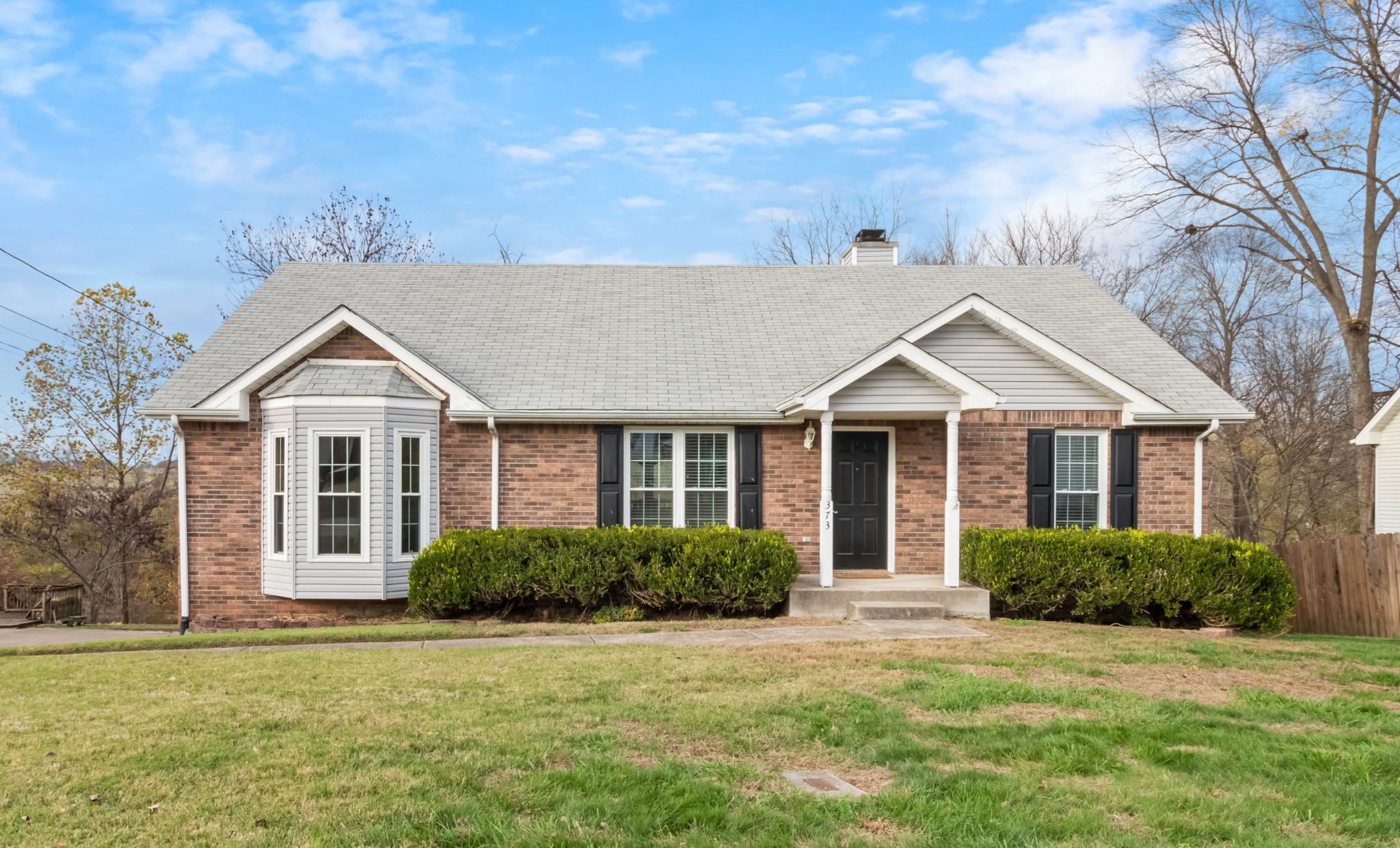 a view of a brick house with a yard and large trees