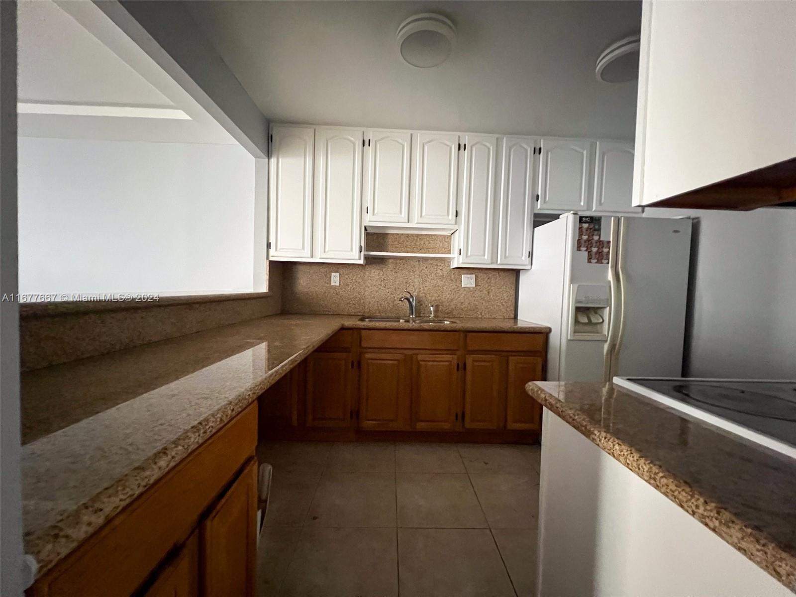 a kitchen with granite countertop a refrigerator sink and stove