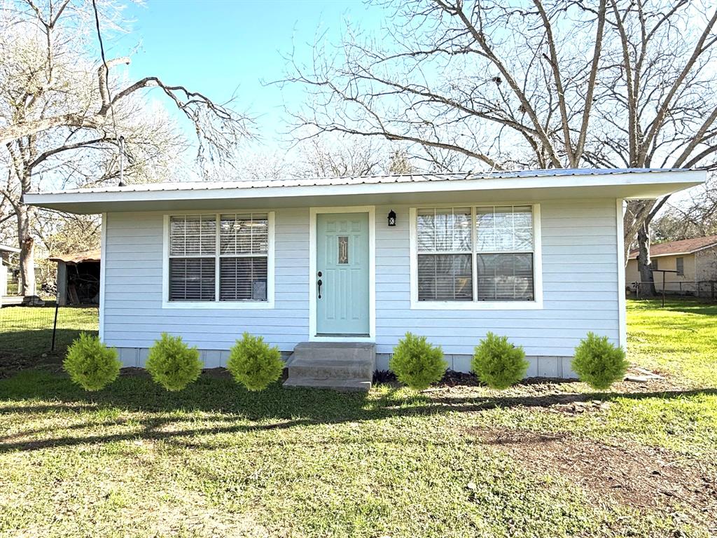 a front view of a house with a yard and potted plants