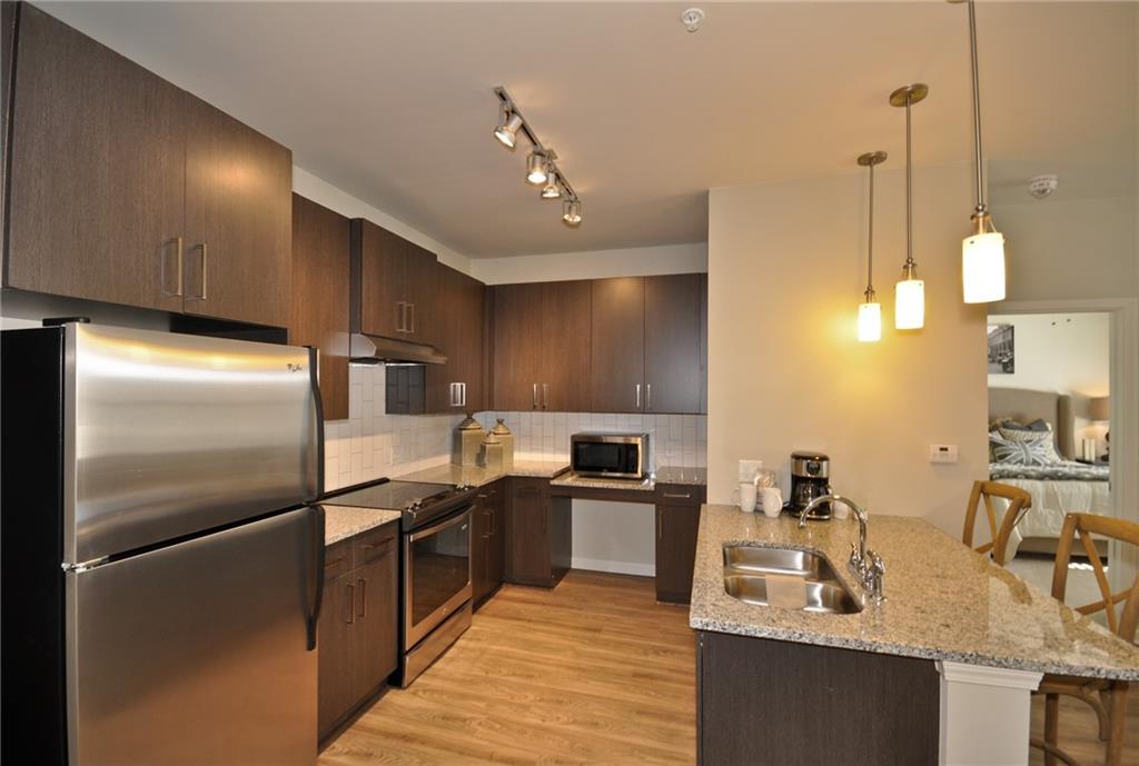 a kitchen with stainless steel appliances granite countertop a sink refrigerator and cabinets