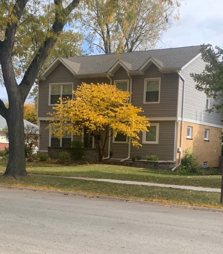 a front view of a house with a yard and potted plants