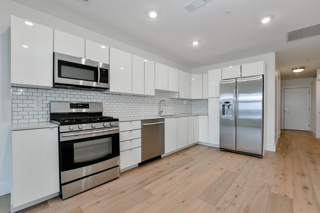 a kitchen with stainless steel appliances granite countertop a stove a sink and a microwave