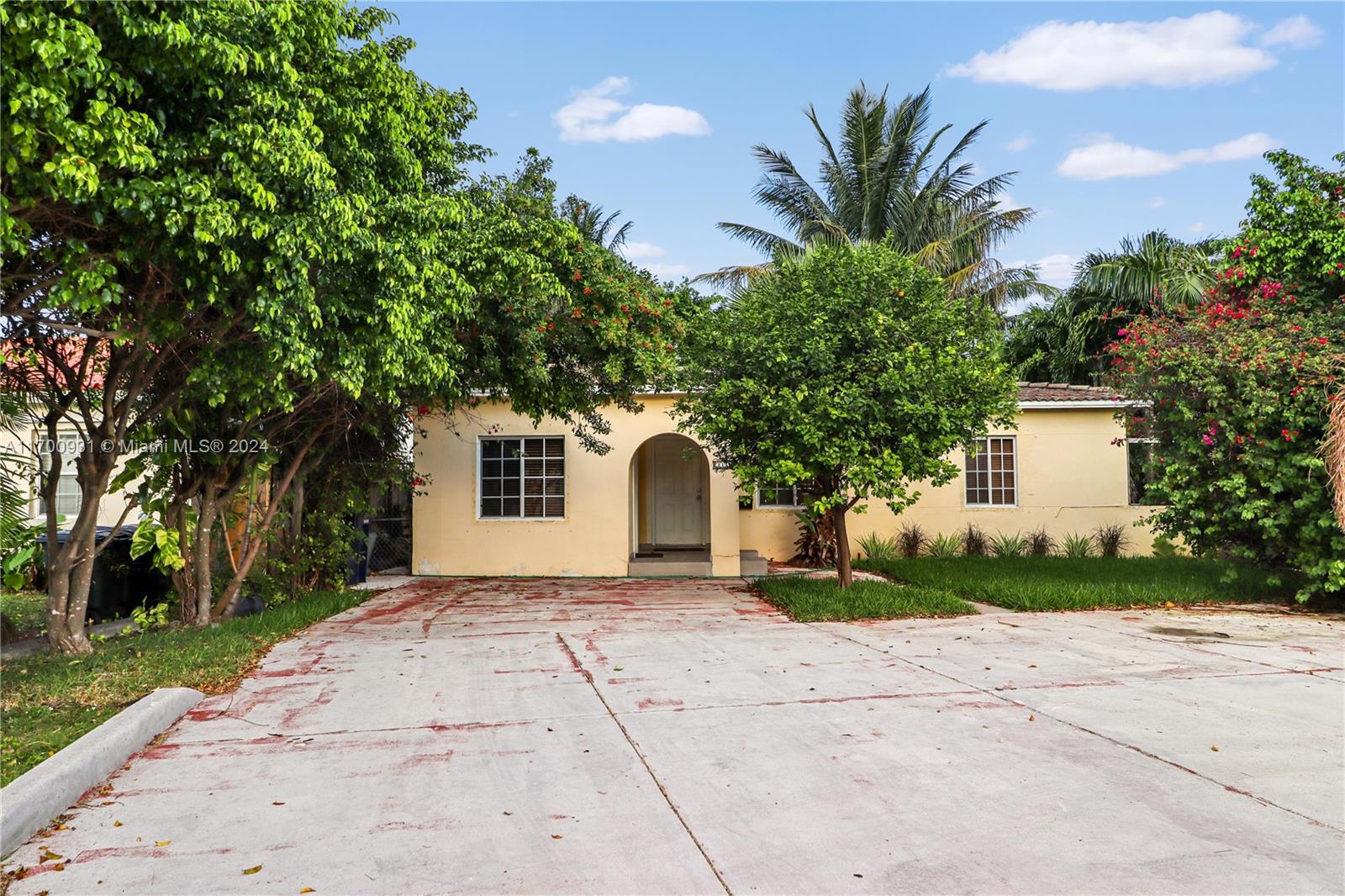 a front view of a house with a garden and trees