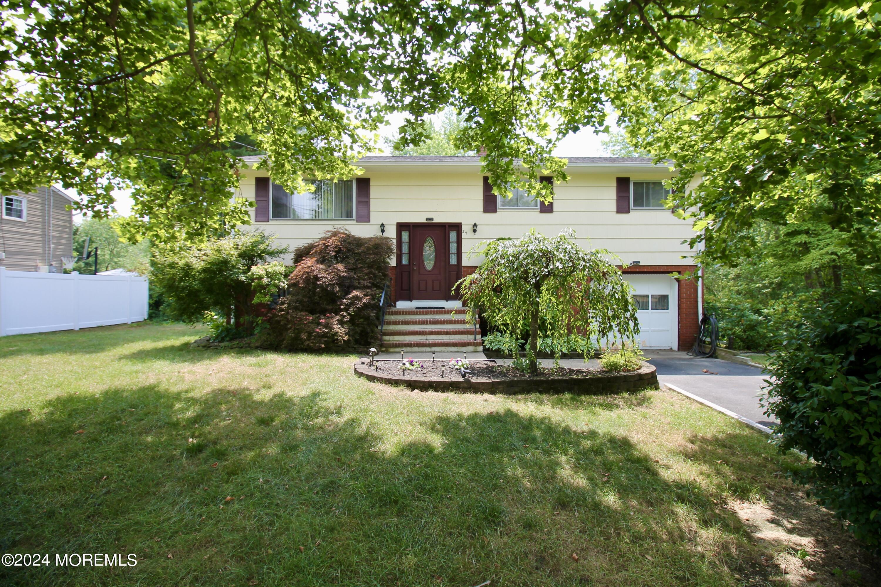 a front view of a house with a garden and tree