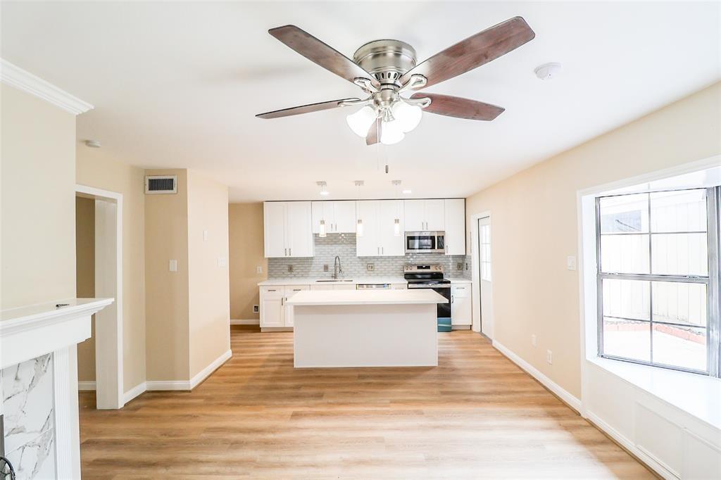 a view of a kitchen with a stove cabinets wooden floor and a ceiling fan