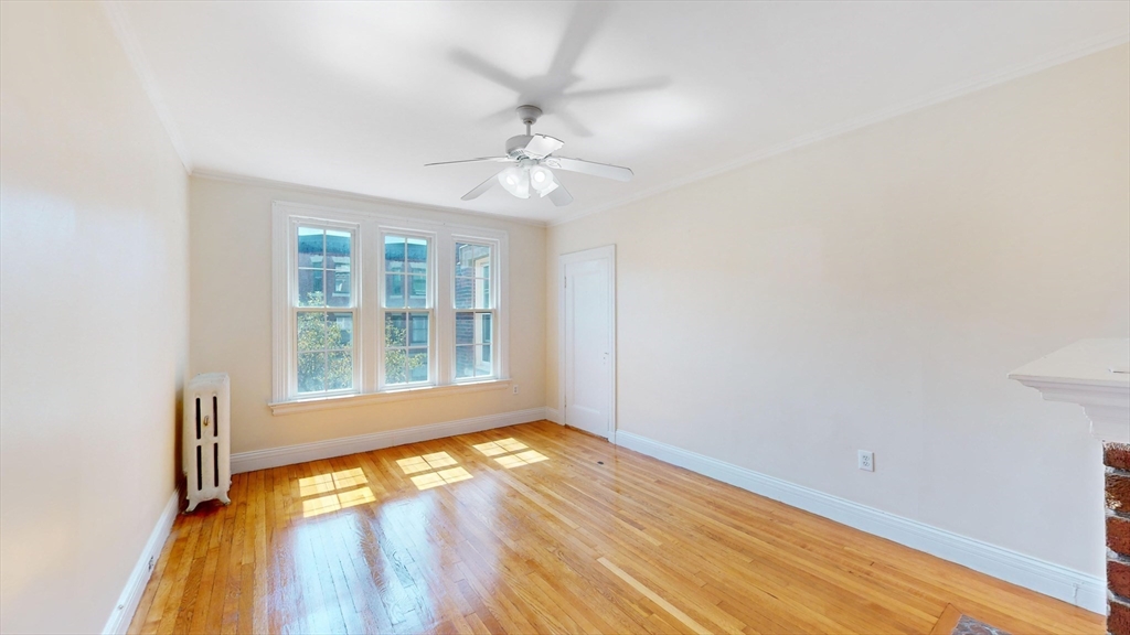 an empty room with wooden floor fan and windows