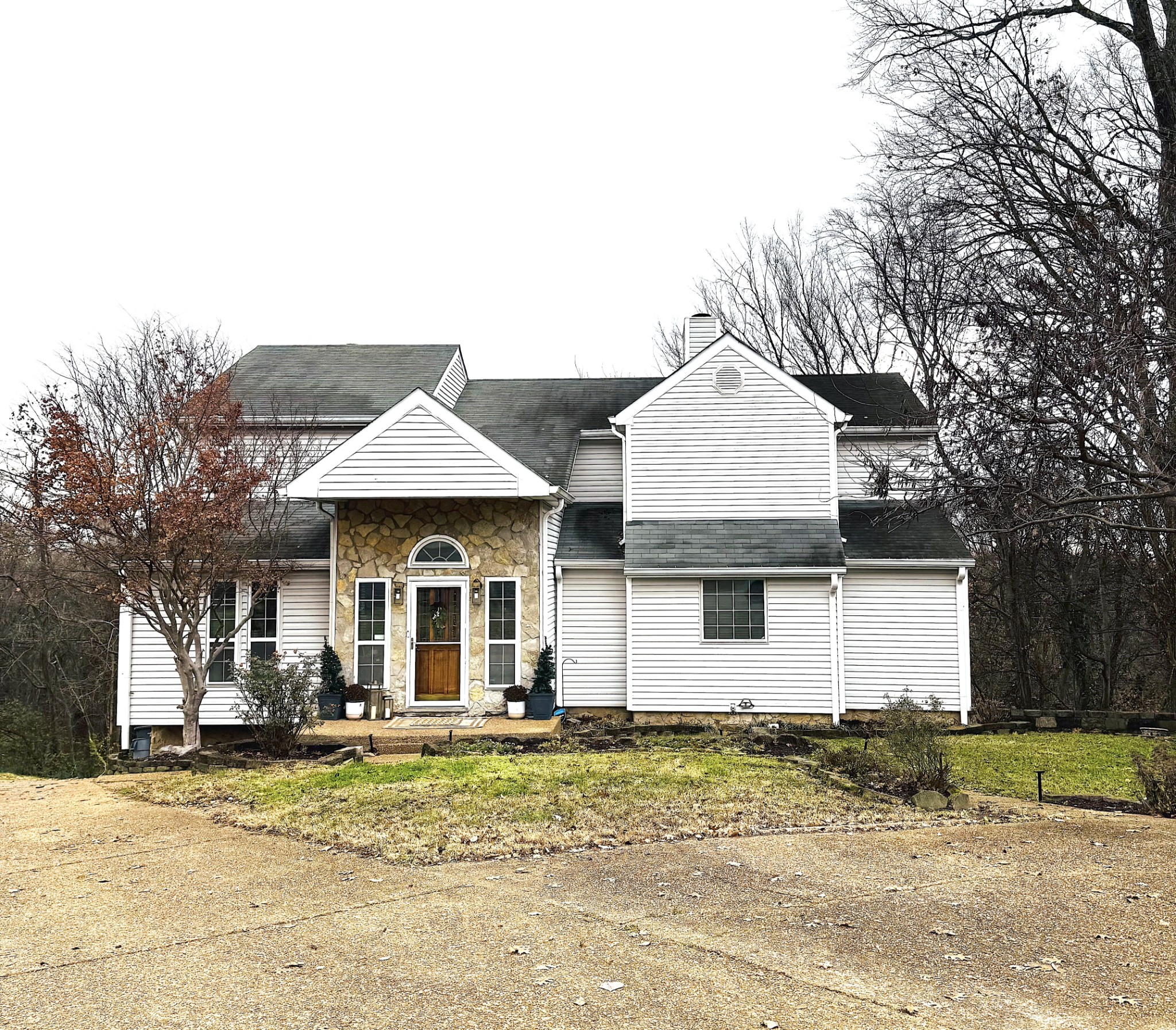 a view of a white house with a large space and large trees