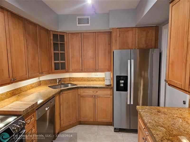 a kitchen with stainless steel appliances granite countertop a refrigerator and a sink