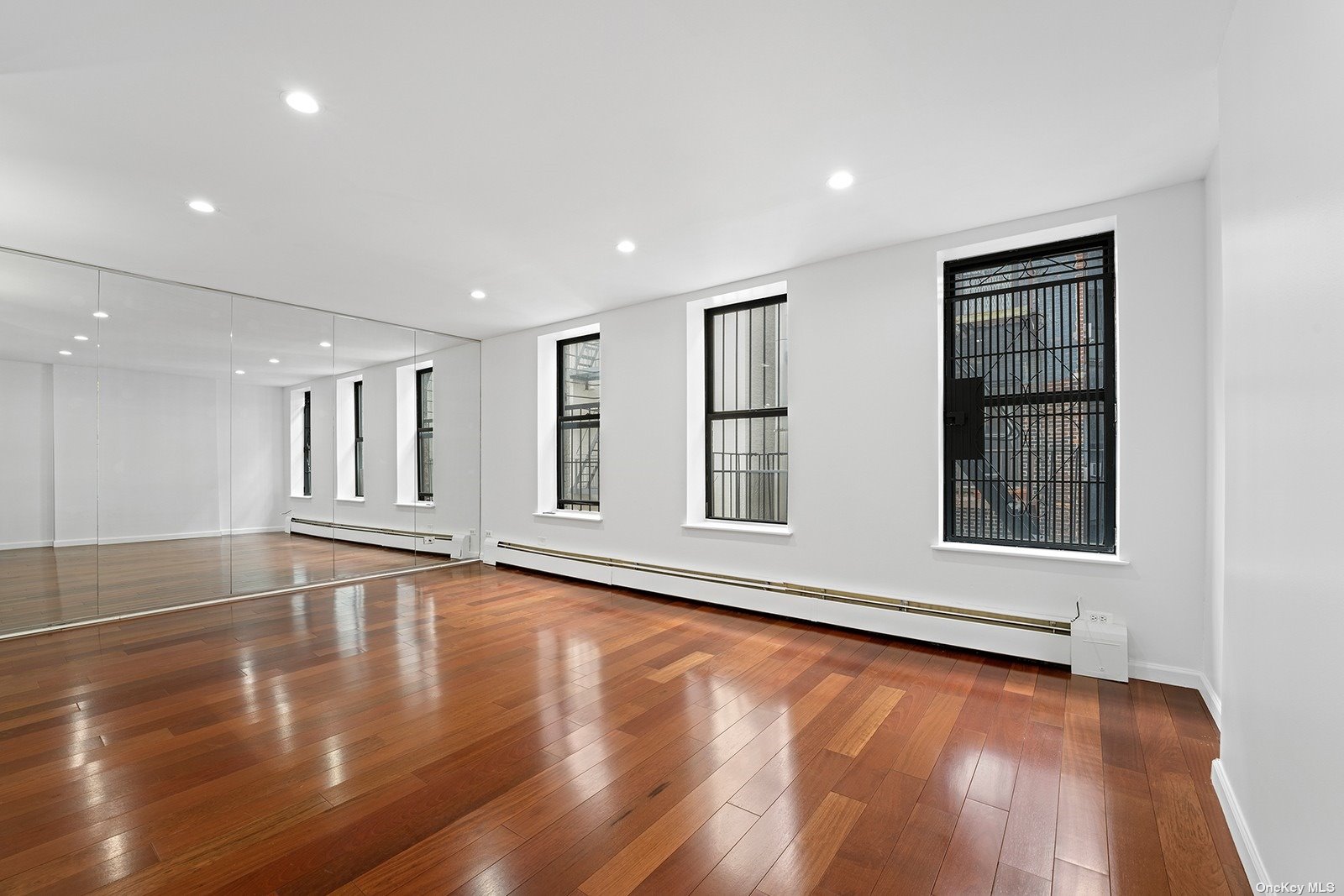 a view of an empty room with wooden floor and window