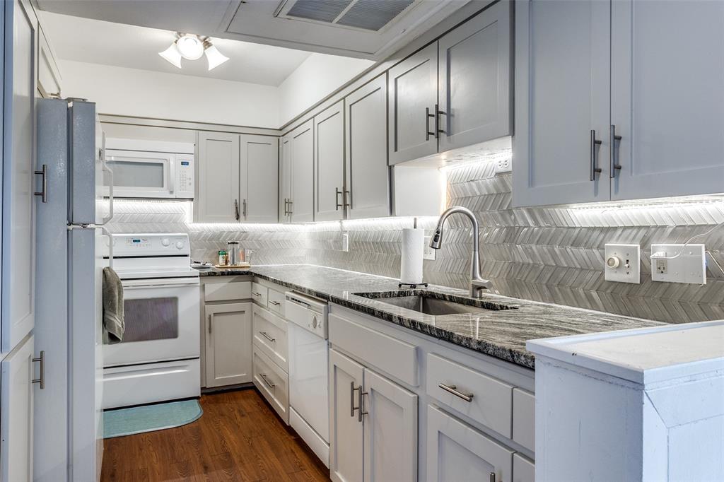 a kitchen with granite countertop a sink stainless steel appliances and cabinets