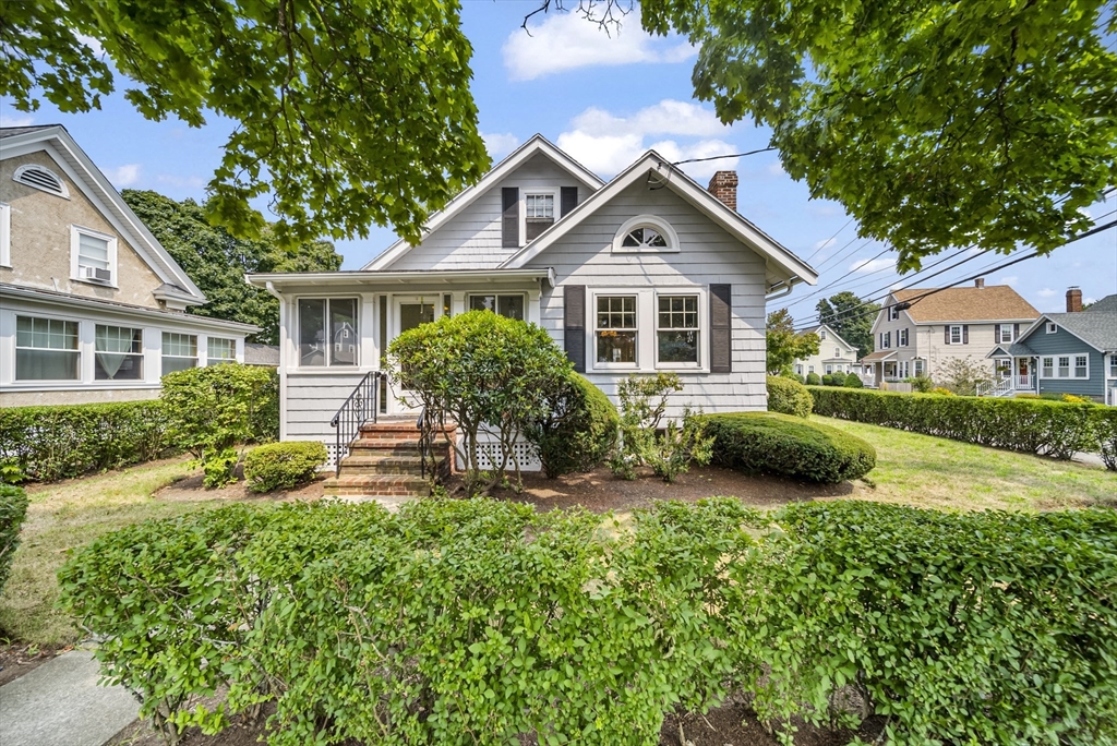 a front view of a house with a yard and potted plants