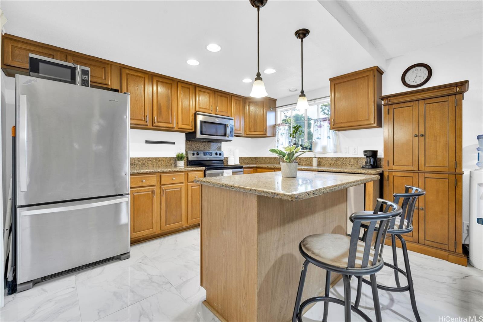 a kitchen with stainless steel appliances granite countertop a refrigerator a sink a stove a dining table and chairs