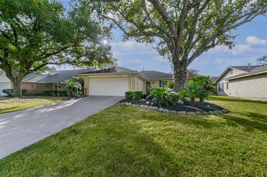 a front view of a house with a yard and a large tree