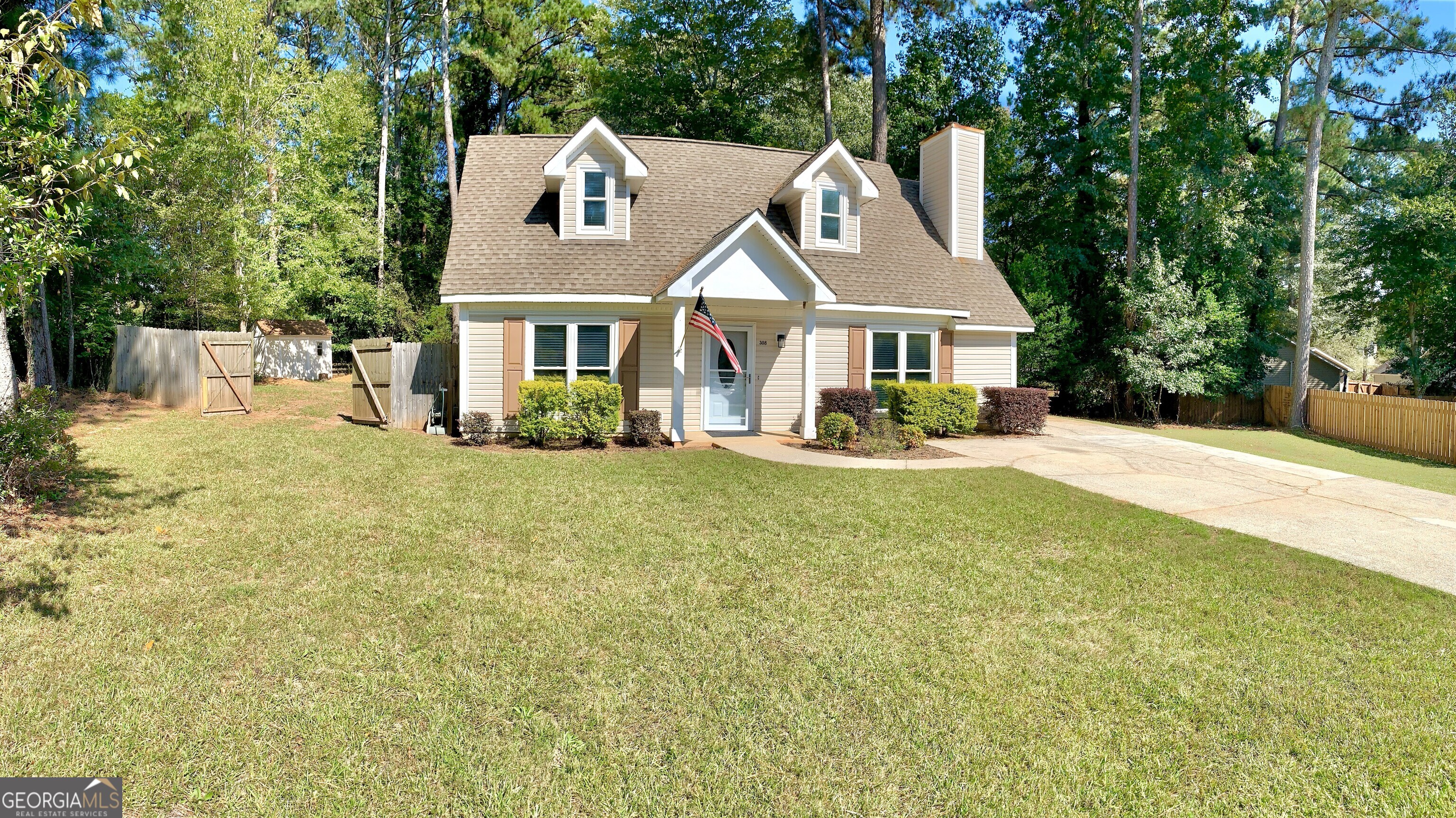 a front view of house with yard and trees in the background