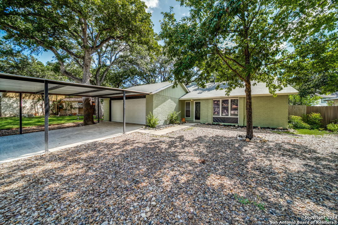 a view of a house with a yard and large tree