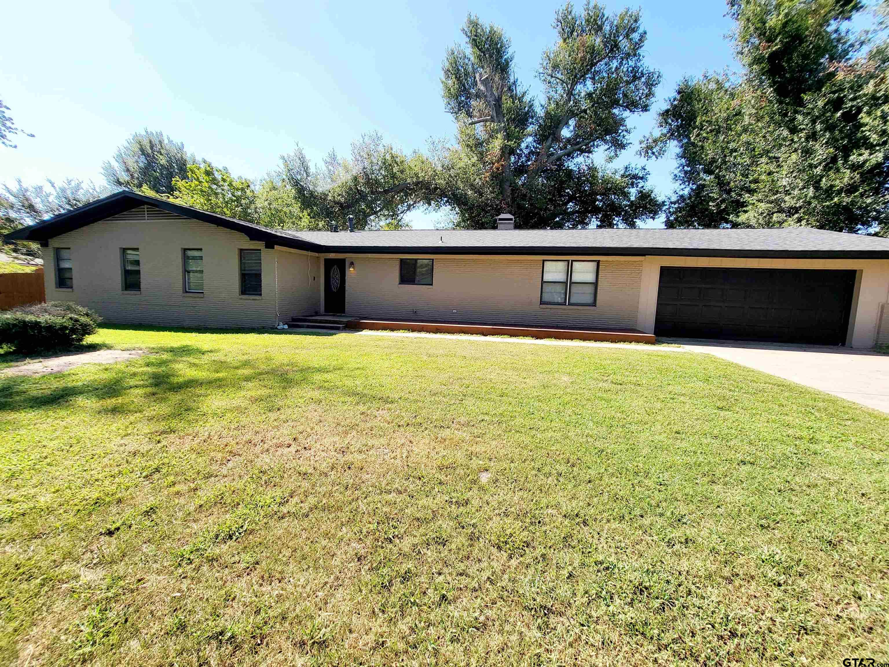 a view of house with yard and trees in the background