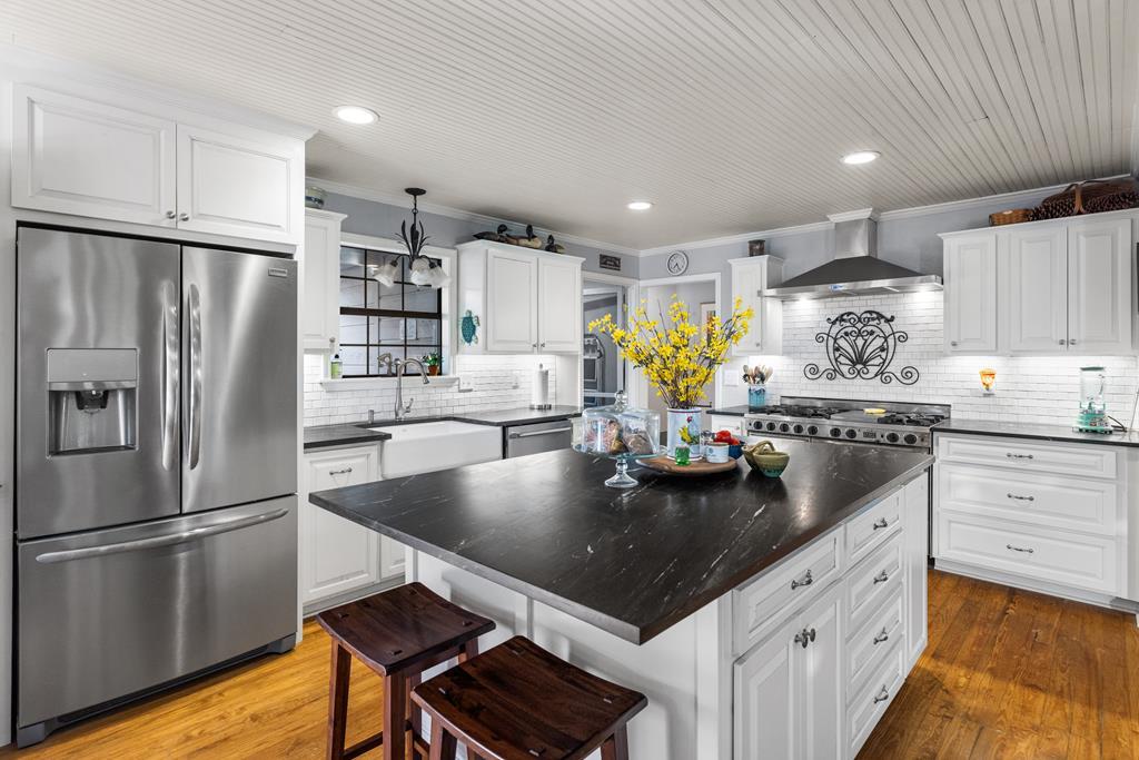 a kitchen with stainless steel appliances granite countertop a refrigerator a stove and a sink with cabinets