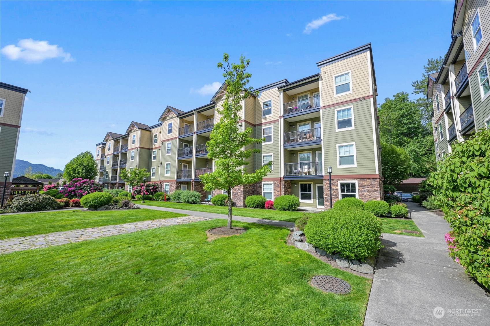 a front view of multi story residential apartment building with yard and green space