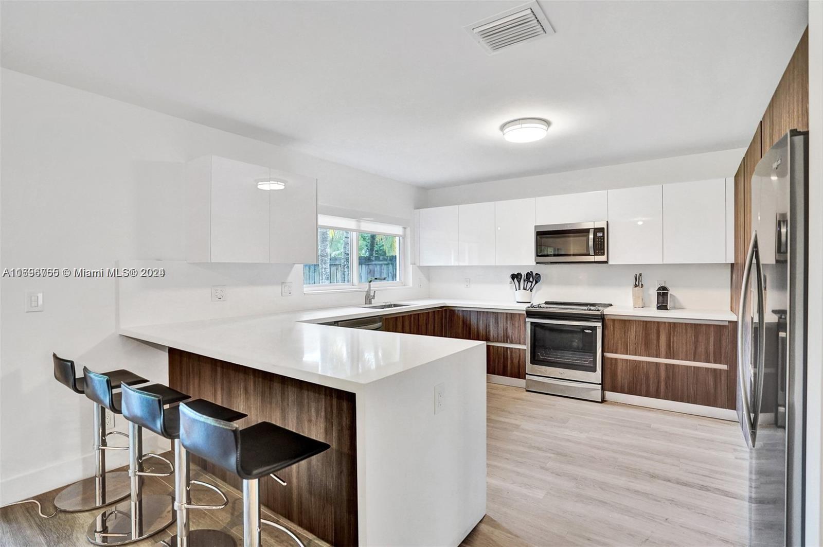 a kitchen with stainless steel appliances a stove a sink cabinets and a wooden floor