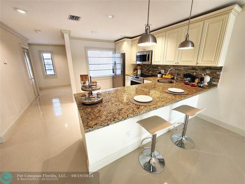 a kitchen with stainless steel appliances granite countertop a sink a stove and a refrigerator