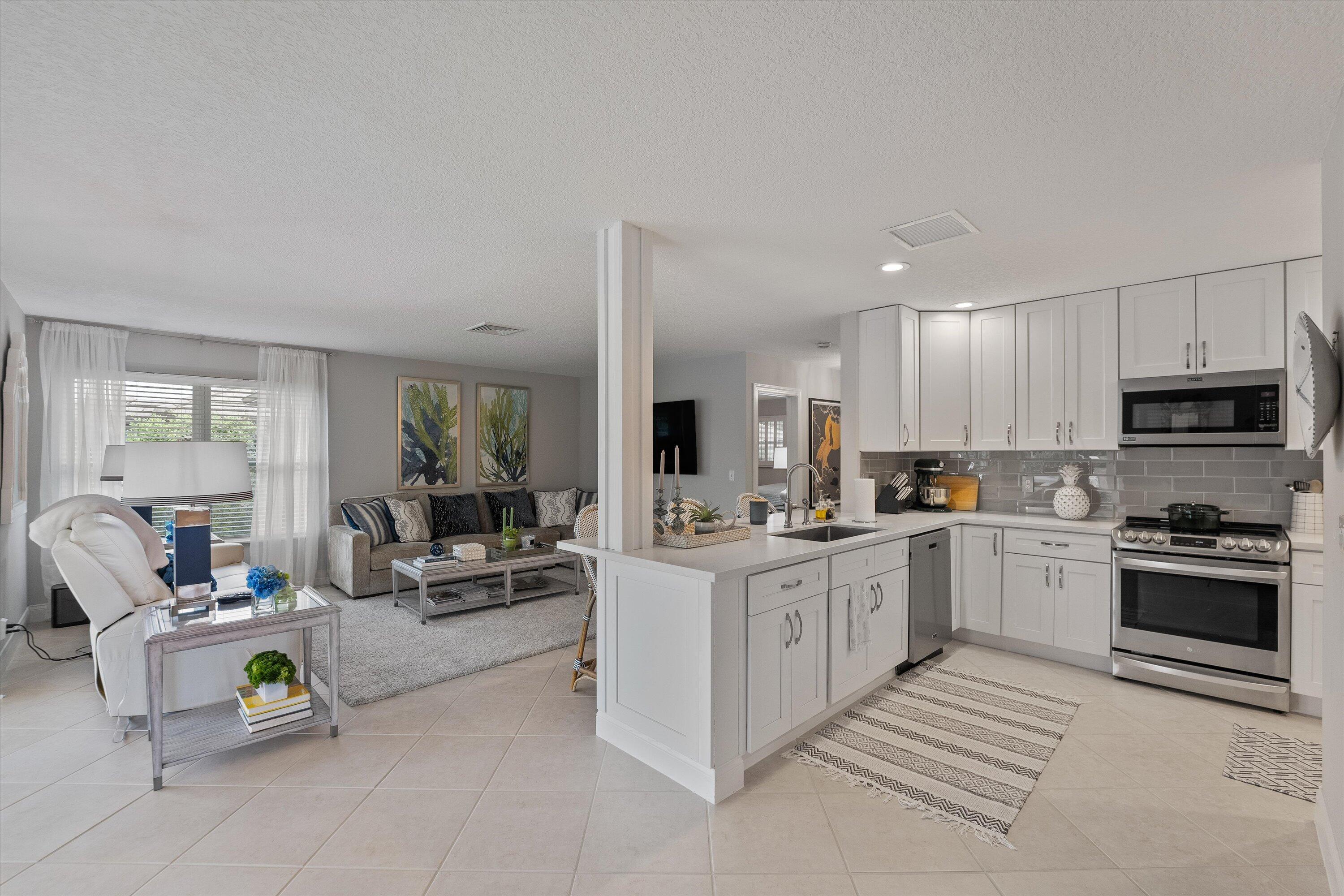 a large white open kitchen with cabinets a sink and a stove