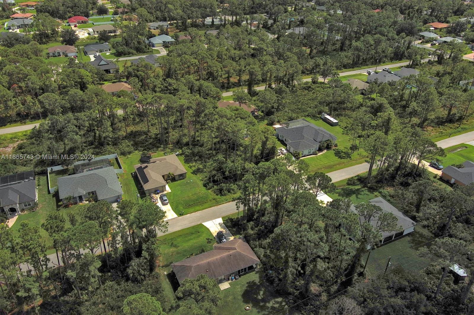 an aerial view of residential houses with outdoor space and trees