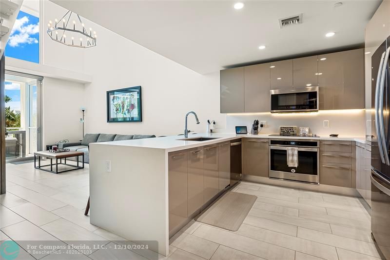 a kitchen with stainless steel appliances granite countertop a stove top oven a sink and a refrigerator