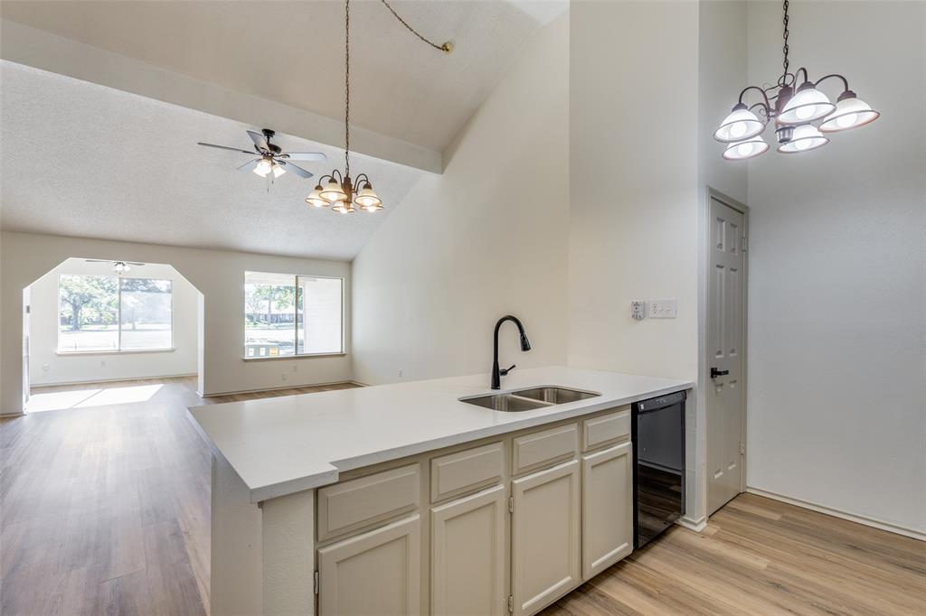 a kitchen with a sink chandelier and wooden floor