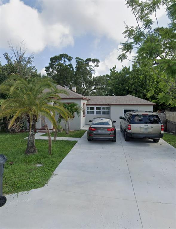 a view of house with car parked beside of road and trees