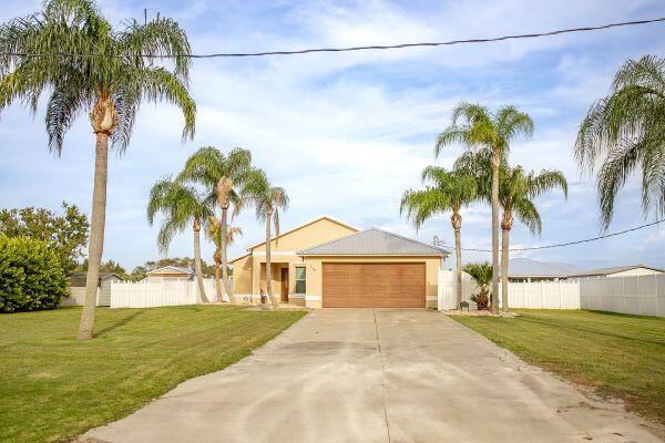 a front view of a house with a garden and palm trees