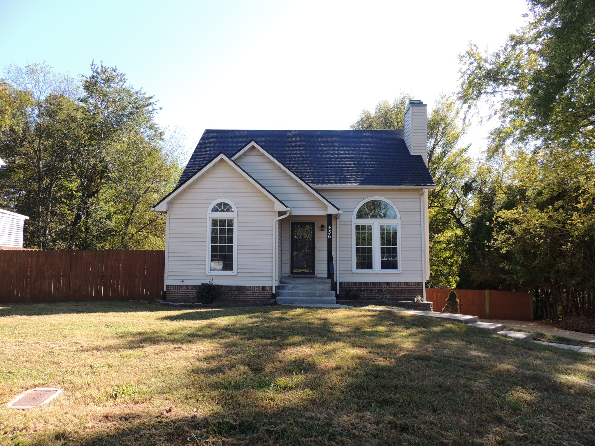 a view of house with yard and trees in the background