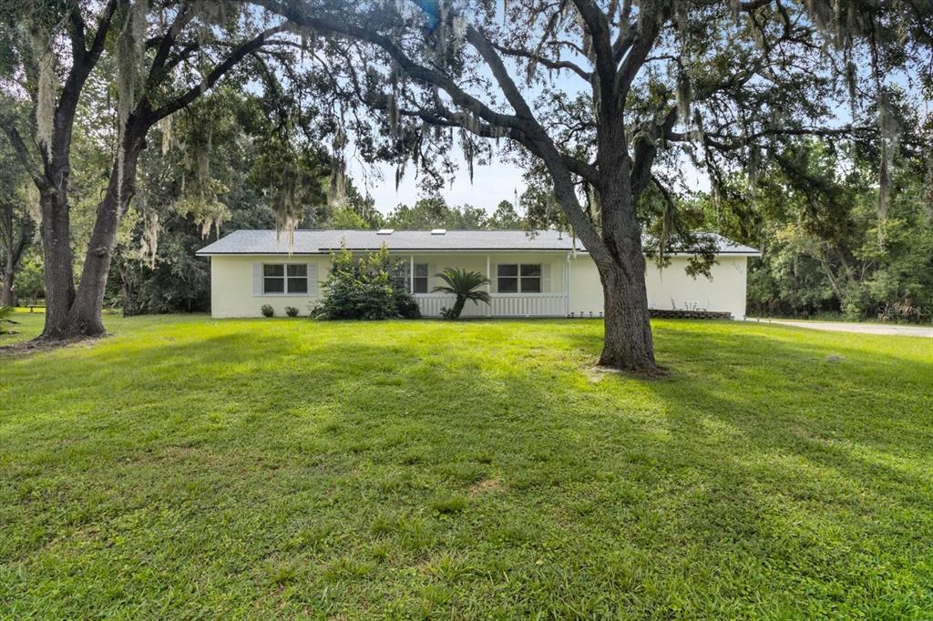 a view of a house with a big yard and large trees