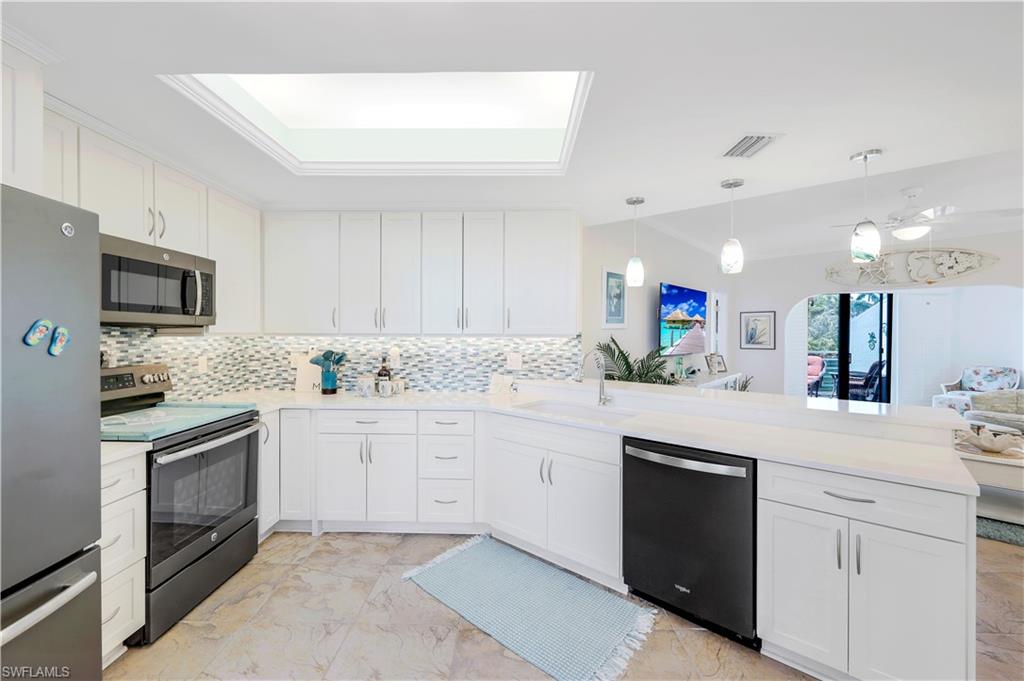 a kitchen with granite countertop a sink stainless steel appliances and white cabinets