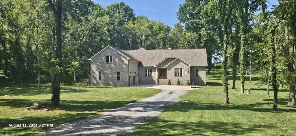 a view of a house with a big yard and large trees