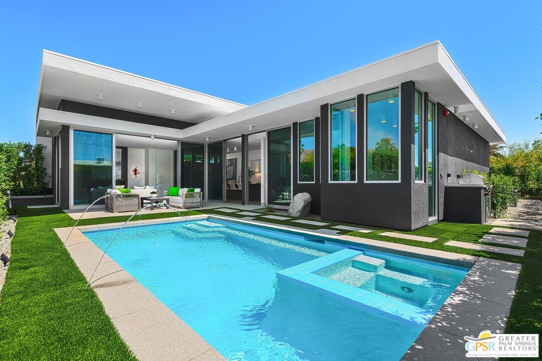 a view of swimming pool with lawn chairs and floor to ceiling window