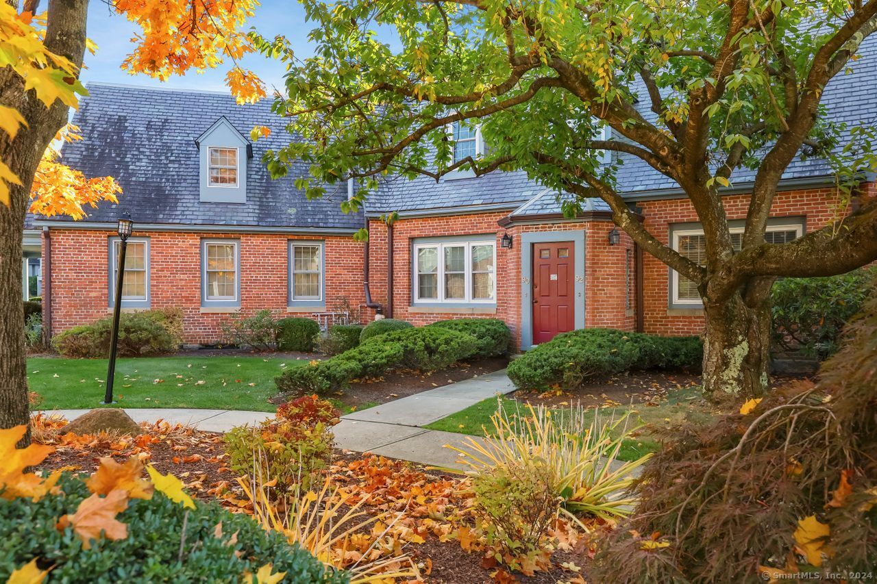 a view of a brick house with a yard and large tree