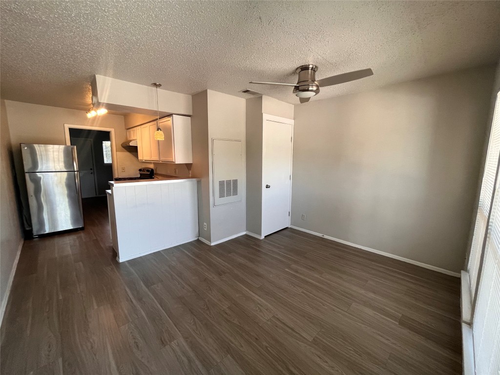 a view of a kitchen with refrigerator and wooden floor